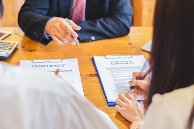 Un couple asiatique lit et signe un contrat à la réunion.