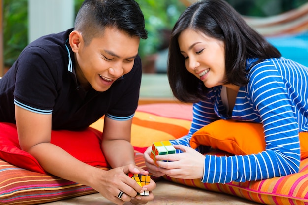 Couple asiatique à la maison jouant avec un cube magique