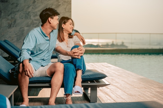 Couple asiatique parlant et s'embrassant près de la piscine avec une vue parfaite sur la merVacances d'été