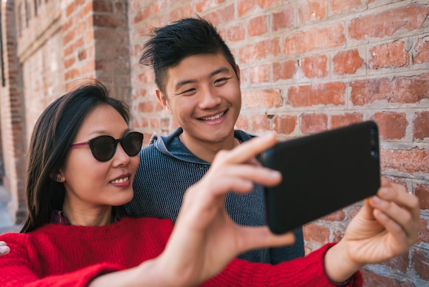 Couple asiatique prenant un selfie avec téléphone portable.