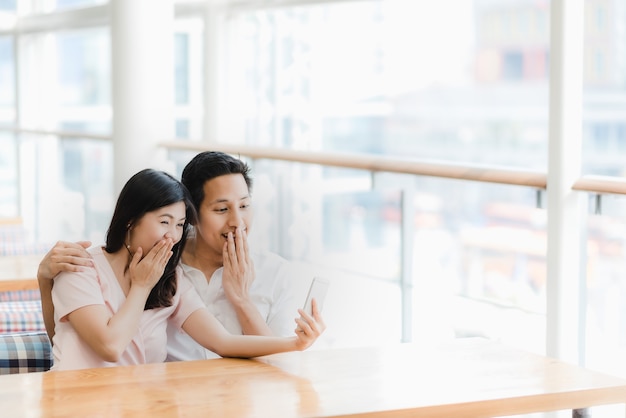 Couple asiatique regardant smartphone et surprenant