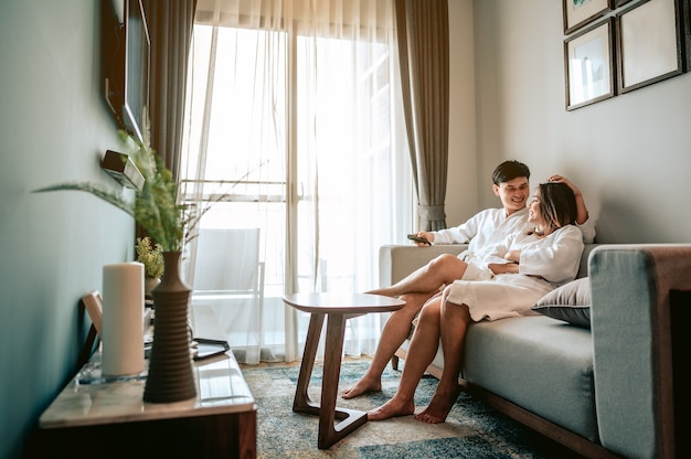 Couple asiatique regardant la télévision assis sur un canapé dans le salon à la maison