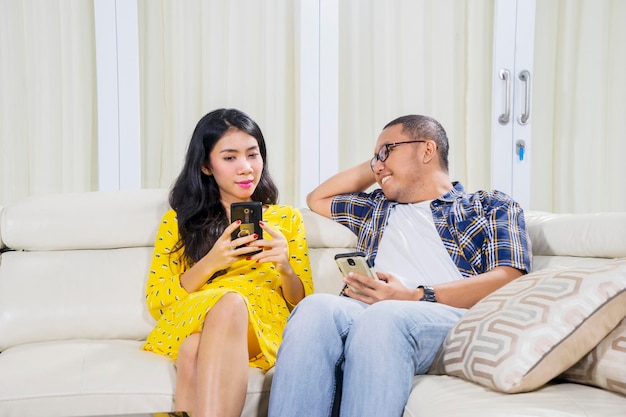 Un couple asiatique se détend avec son téléphone à la maison.