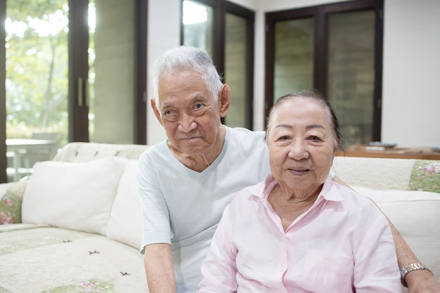 Couple asiatique senior s'embrassant sur le canapé