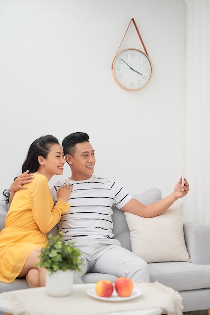 Couple asiatique utilisant un smartphone pour selfie dans le salon à la maison