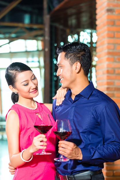 Couple asiatique avec verre de vin rouge