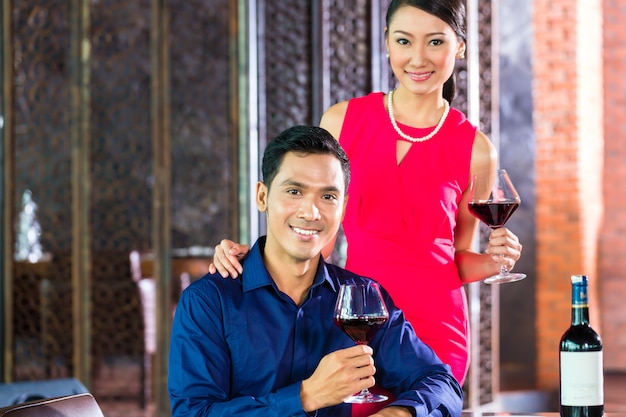 Couple asiatique avec verre de vin rouge