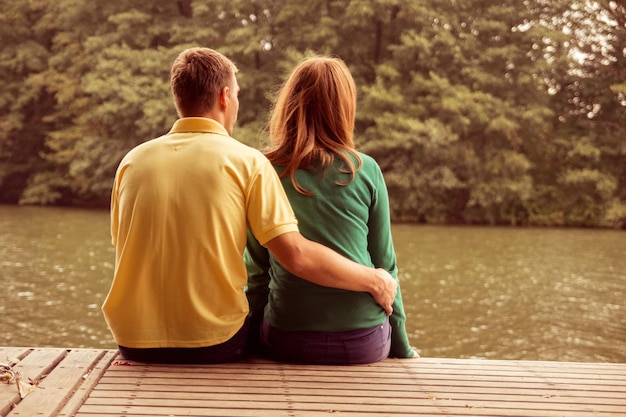 Un couple assis au bord de l'eau et s'embrassant