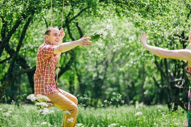 Couple assis sur une balançoire dans le parc. Jardin vert.