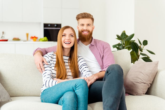 Couple assis sur un canapé à la maison et regarder la télévision