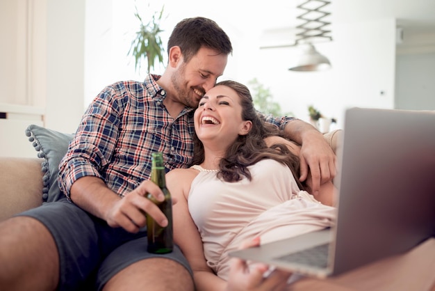 Couple assis sur un canapé et utilisant un ordinateur portable dans le salon