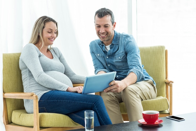 Couple assis sur une chaise et à l&#39;aide d&#39;une tablette numérique