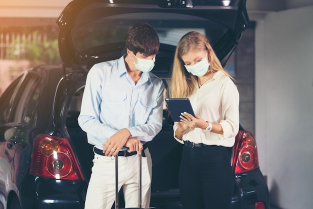 couple assis à côté de la voiture avec masque