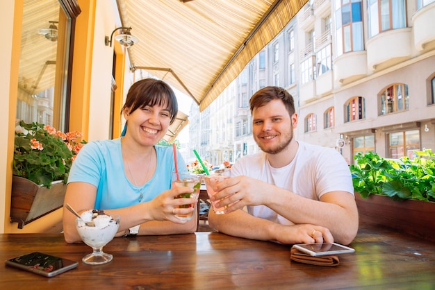 Couple assis dans un café d'été buvant des boissons fraîches et parlant