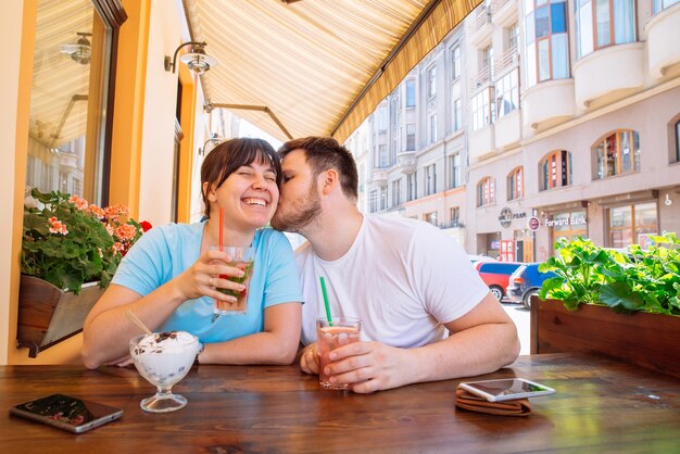 Couple assis dans un café d'été buvant des boissons fraîches et parlant