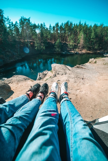 Couple assis dans le lac de coffre de voiture sur les jambes de fond en baskets et jeans concept de voyage