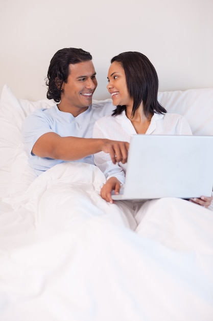 Couple assis sur le lit à surfer sur Internet