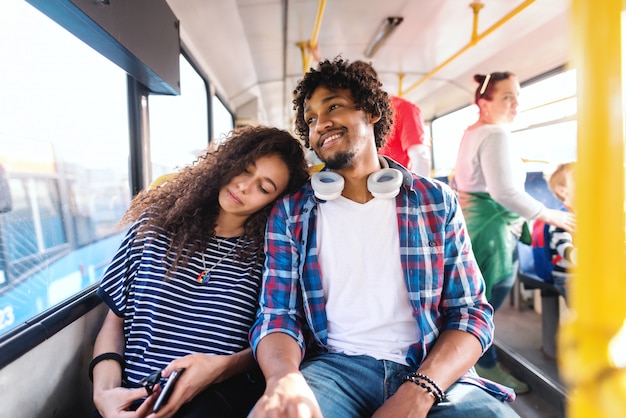 Couple assis et monté dans le bus de la ville. Fille endormie et penchant la tête sur l'épaule de son petit ami.