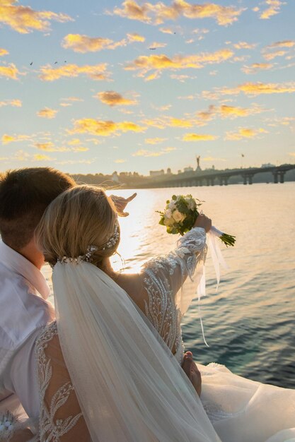 Photo un couple assis près de la mer au coucher du soleil