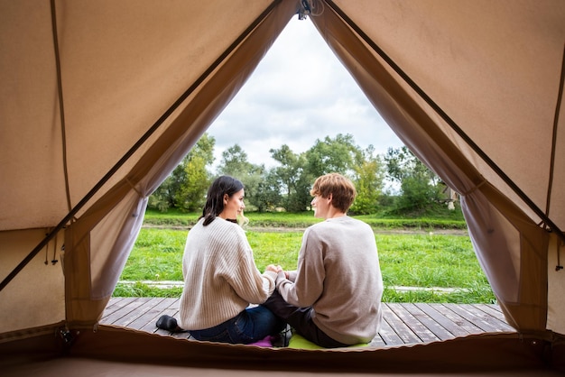 Un couple assis près d'une tente au glamping