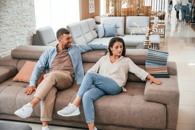 Couple assis et relaxant choisissant le canapé et le lit dans le magasin