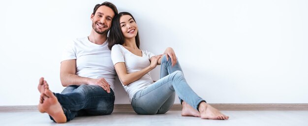 Photo le couple assis sur le sol sur le fond du mur blanc