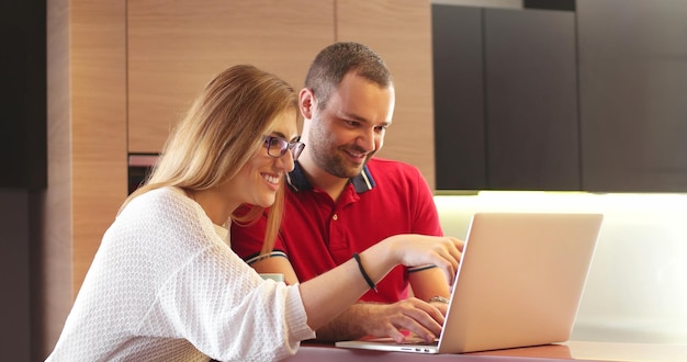 Couple assis à table faisant un achat en ligne par carte de crédit