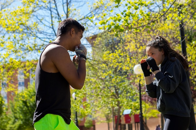 Photo couple d'athlètes pratiquant la boxe à l'extérieur.