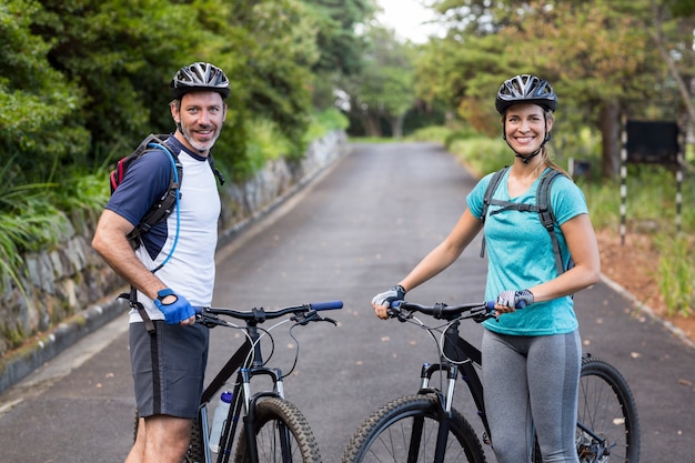 Couple athlétique debout avec vélo de montagne sur la route ouverte