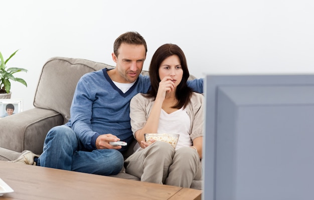 Couple attentif regardant un film d&#39;horreur à la télévision