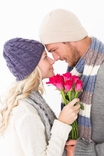 Couple attractif dans des vêtements chauds, tenant des fleurs