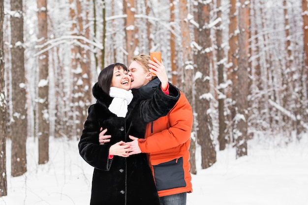 Couple attrayant faisant selfie à l'extérieur en hiver