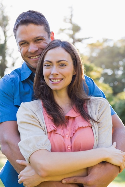 Couple attrayant, souriant à la caméra et embrassant