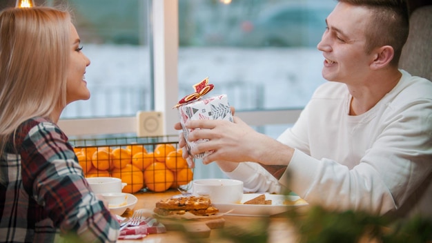 Un couple au café un homme tenant un petit cadeau de noël