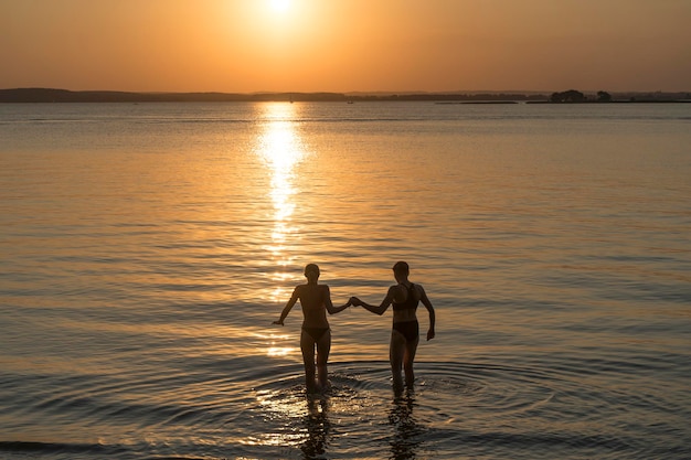 Couple au coucher du soleil dans l'eau Un couple heureux d'amoureux se promène le long de la plage par un bel été