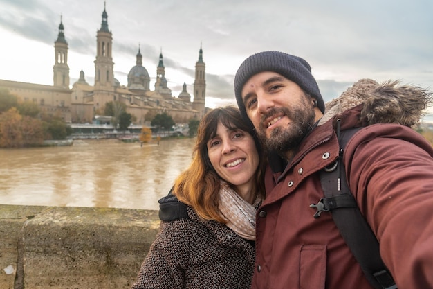 Un couple au coucher du soleil sur le pont de pierre à côté de la Basilique De Nuestra Senora del Pilar