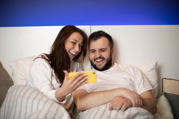 Couple au lit regarde smartphone