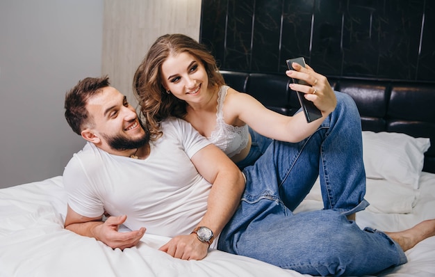 Couple ayant une conversation vidéo avec des amis au lit à la maison