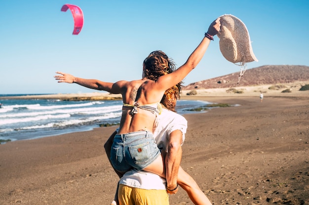 Couple de beaux adultes se fiancent et se marient ensemble à la plage - femme sur les épaules de l'homme le regardant et souriant