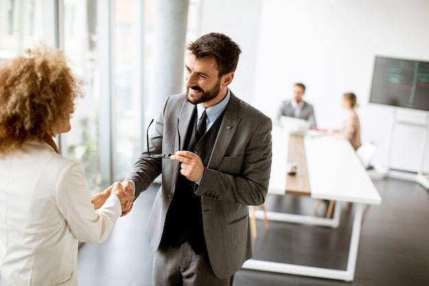 Couple de beaux gens d'affaires multiethniques poignée de main au bureau