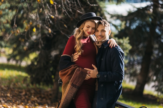 Un couple de beaux jeunes futurs parents passe du temps dans le parc d'automne, une jeune femme enceinte et un ...