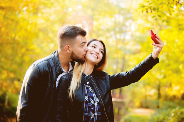 Couple blanc fait un selfie sur un téléphone portable dans un parc