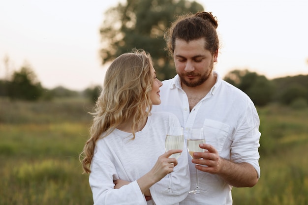 Couple boit du champagne le soir près du lit dans la nature