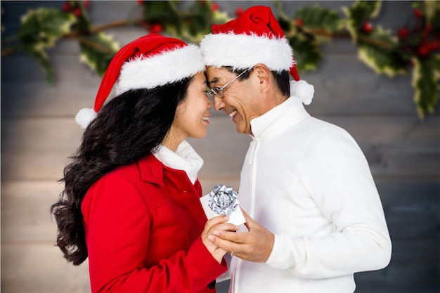 Couple en bonnet de noel tenant un cadeau