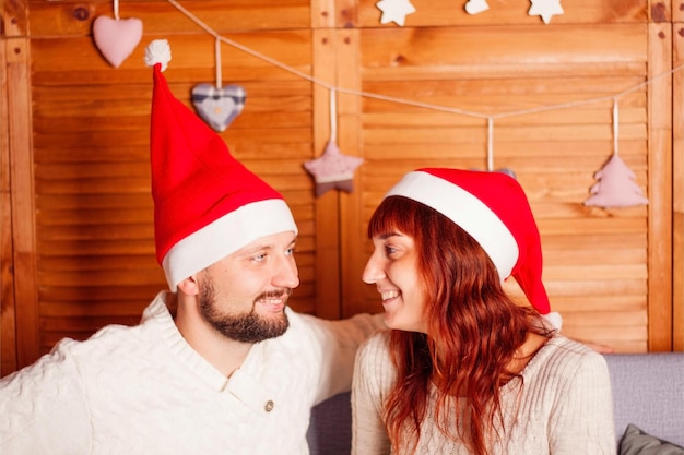 Un couple en bonnets de noel se regarde