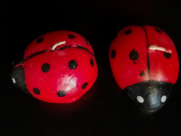 Couple de bougies rouges et noires en forme de coccinelle sur fond noir concept de décoration à la maison