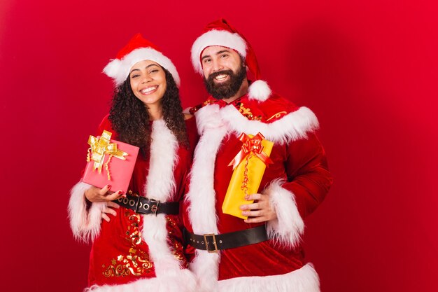 Couple brésilien habillé pour noël père noël maman noël échange de cadeaux approuvé femme noire et homme de race blanche