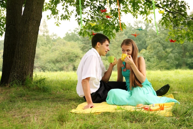 Couple buvant du thé dans le parc sous un arbre