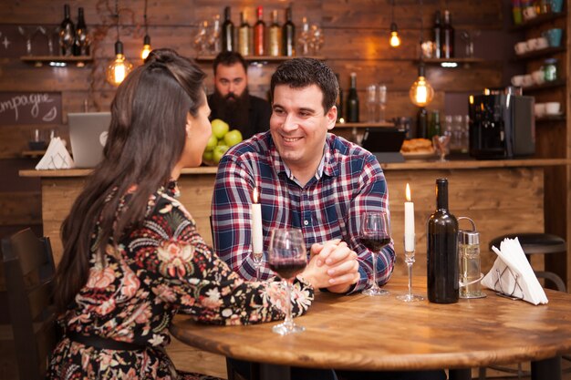 Couple buvant du vin rouge et partageant un beau moment dans un pub hipster. Temps de joie.