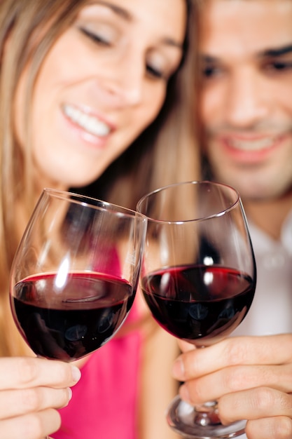 Couple buvant du vin rouge tinter des verres